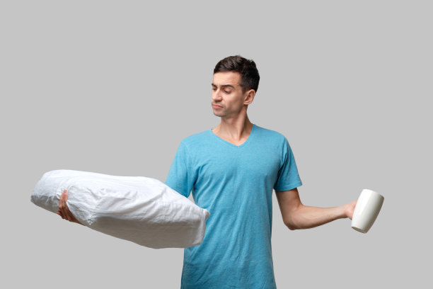 年轻的黑发男子在白色的咖啡和白色的枕头之间选择图片下载