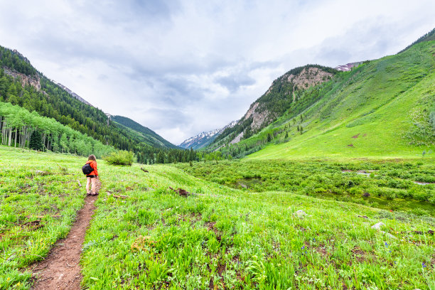 2019年夏天，科罗拉多州阿斯彭的Conundrum Creek Trail上的人行道道路的广角视图，一个女人站在多云的暴风雨天空中图片下载