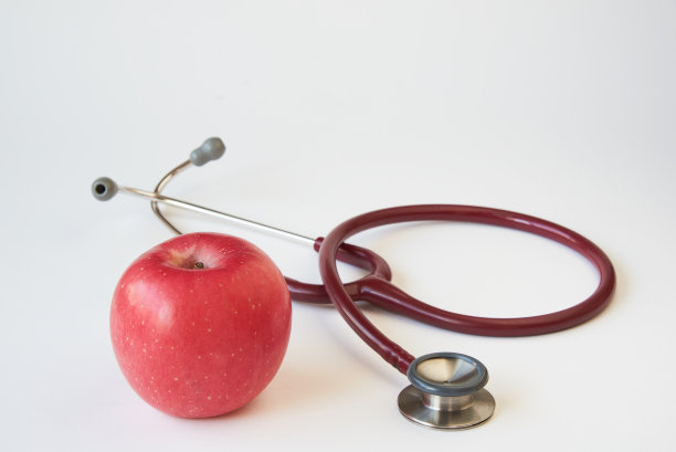 一个美味的红苹果和一个红色的听诊器。图片下载