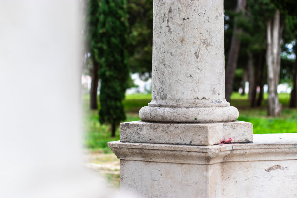 古罗马大理石柱子，另一根柱子在前景中失去了焦点。绿色公园在远处图片下载