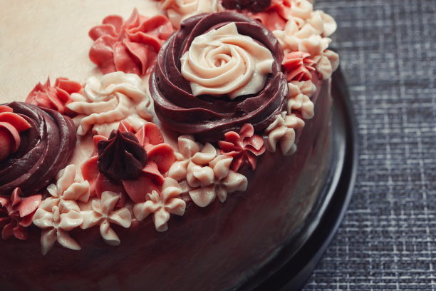 深色背景上有奶油花的粉红色蛋糕图片下载