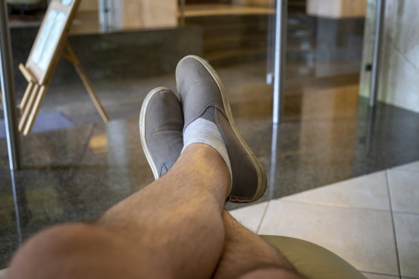 男人脚上灰色运动鞋放松在沙发上图片下载