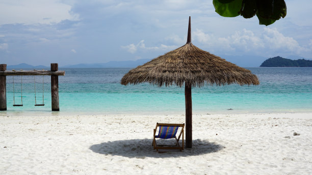 户外蓝色海洋背景的海滩上，天然的叶子热带阳伞图片下载