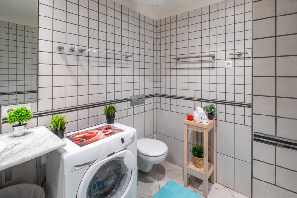 浴室内部，墙壁和地板上铺着灰色瓷砖。洗衣机。图片下载