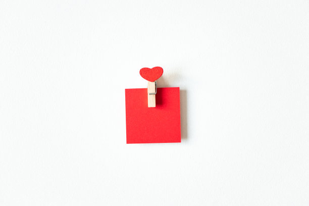 红心木制迷你晾衣夹和纸空白的笔记在白色的背景，上面。可爱的情人节卡片或婚礼派对邀请图片下载