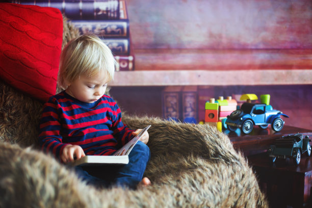 可爱的蹒跚学步的男孩，在家里看书图片下载