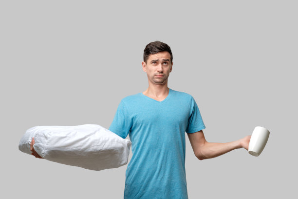 年轻的黑发男子在白色的咖啡和白色的枕头之间选择图片下载