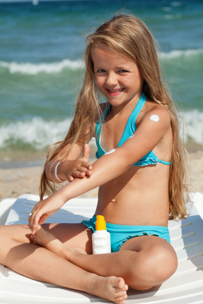 小女孩在明亮的阳光下涂防晒霜图片下载