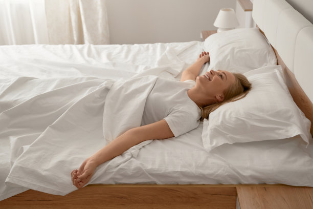 女孩在床上享受阳光。图片下载