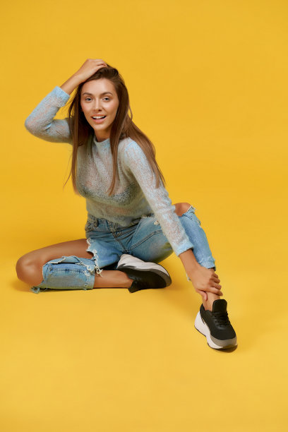 漂亮女孩坐着，腿向前，手掌放在头上图片下载