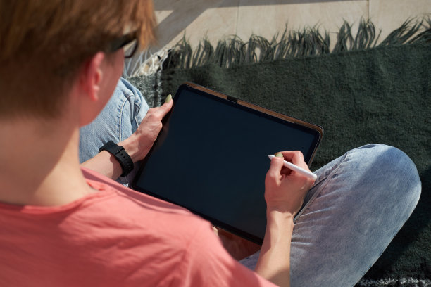 自由职业者数字插画工作在平板电脑上，而坐在格子在阳光阳台图片下载