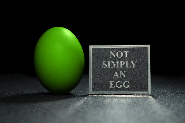 绿色鸡蛋，盘子上写着“不仅仅是鸡蛋”。黑色背景上的绿色鸡蛋。С等空间。食物的照片图片下载