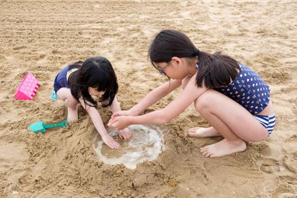 两个亚洲小女孩在沙滩上玩沙子图片下载
