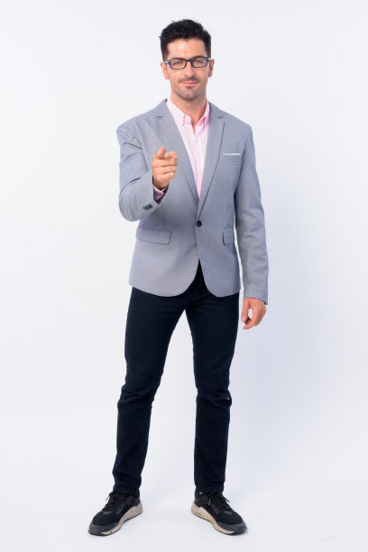 全身拍摄的年轻英俊的商人与眼镜指向相机图片下载