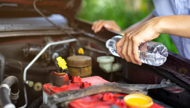 近距离的技师拿着蒸馏水，并在管道中注入维修汽车的概念图片下载