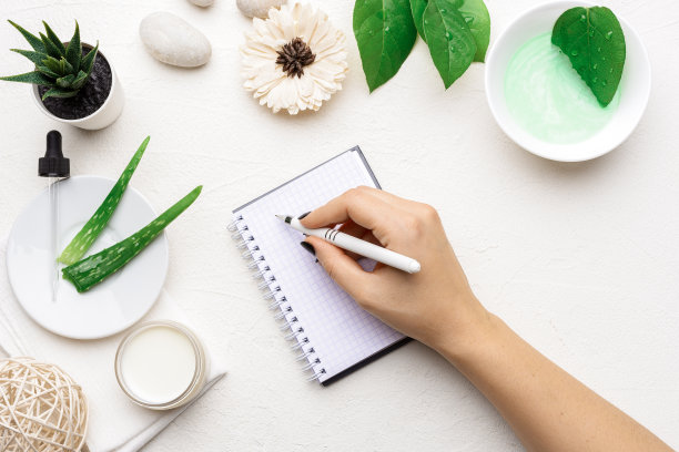 新鲜和天然芦荟化妆品背景与空白空间和空白纸记事本。手工护肤产品配方。面部护理准备及爽肤霜背景。女人的手写作图片下载