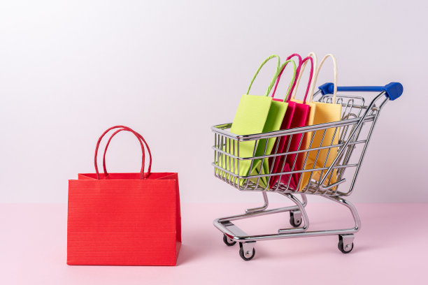 购物手推车上的彩色纸袋，背景明亮。创意简约的购物理念。图片下载