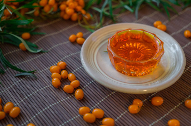 成束的成熟的，橙色的沙棘在树枝上与沙棘油。图片下载