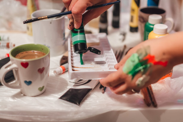 艺术家在调色板上和手上混合不同的颜色。在演播室喝咖啡图片下载