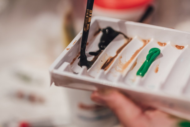 这是一幅特写，画家的画笔刷毛正在调色板上涂抹黑色颜料图片下载