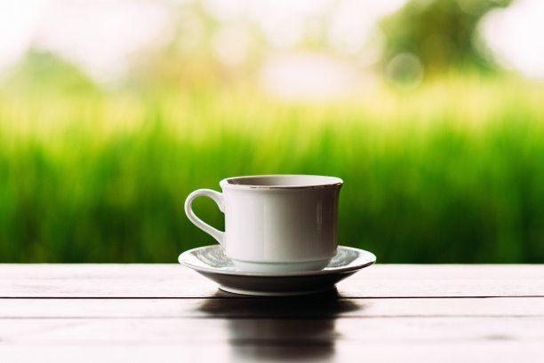 白色的茶杯在美丽的背景上。在巴厘岛的梯田背景上的白咖啡杯。茶碟上的白色茶杯。杯子在美丽的背景上。特写照片的一个杯子图片下载