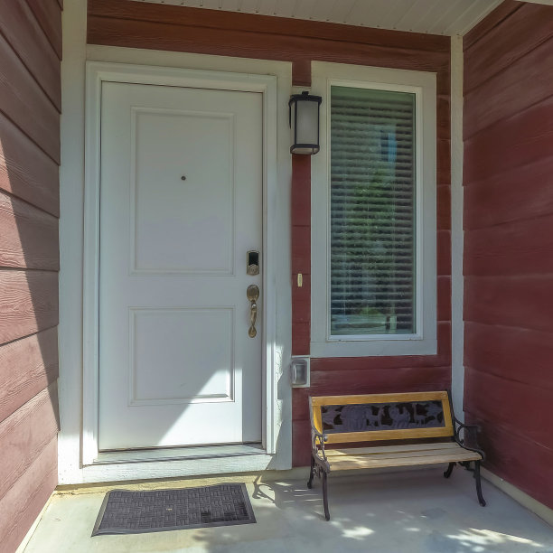 白色的前门和窗户旁有一条长凳，紧邻联排别墅的立面图片下载