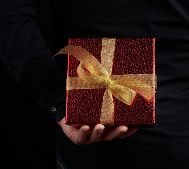 男人的手拿着一个红色的纸盒，背后藏着一份礼物图片下载
