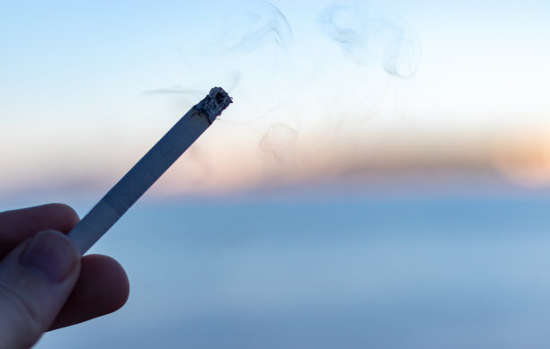 手里拿着一根香烟，黑色的形象，烟雾在空气中可见图片下载