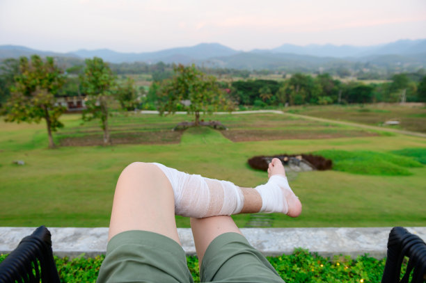 腿上缠着绷带的人在户外的草地上休息图片下载