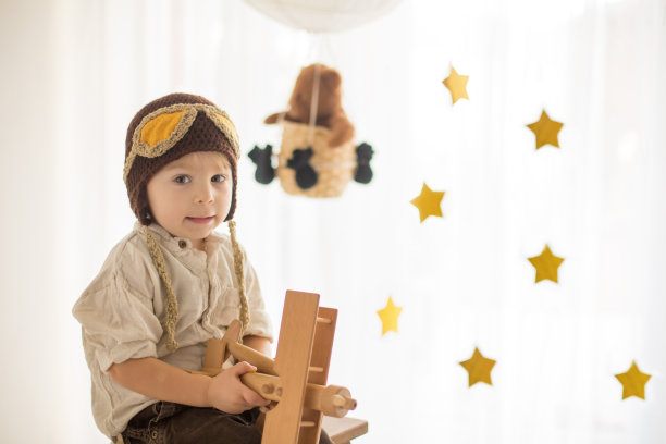 可爱的蹒跚学步的男孩，玩飞机和泰迪熊，气球和身后的玩具图片下载