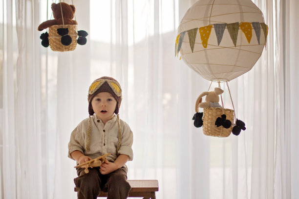 可爱的蹒跚学步的男孩，玩飞机和泰迪熊，气球和身后的玩具图片下载