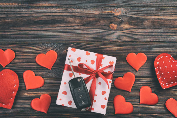 情人节或其他节日手工礼物在纸与红心，汽车钥匙和礼盒在节日包装。盒子上的礼物在深色的木制桌子的顶部查看与复制空间，空的空间设计图片下载