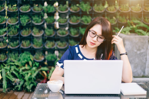 在户外办公室用笔记本电脑和时钟工作的亚洲女性。图片下载