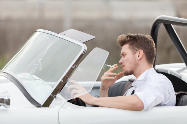 英俊的男人在一辆老爷车旁抽烟图片下载