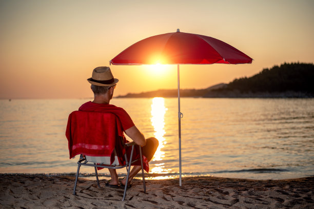 日落时分，一个男人在海滩上放松的剪影图片下载