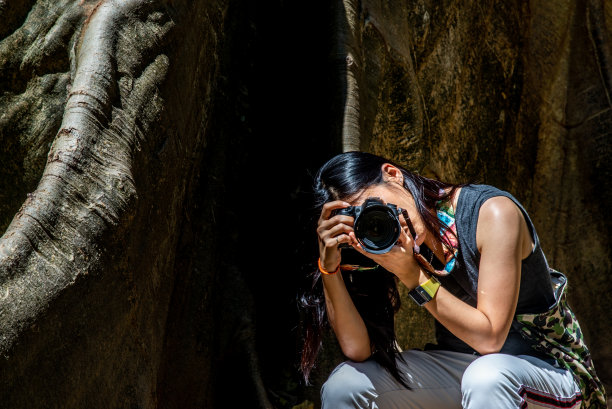 泰国乌泰他尼省班萨纳姆，一名年轻女子背着背包，用相机拍摄大树。图片下载