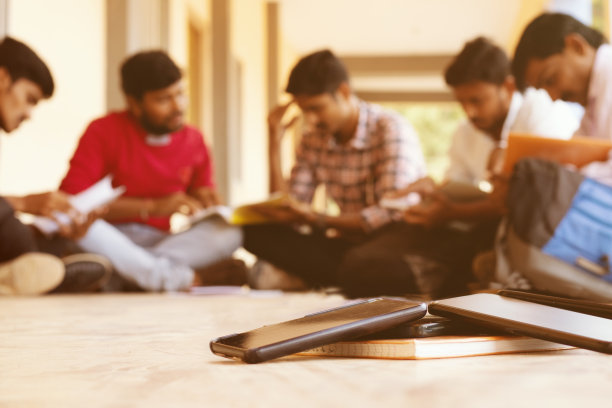 选择性地专注于手机，一群学生忙于阅读，避免智能手机分心——这是年轻人在阅读时沉迷于手机的概念。图片下载