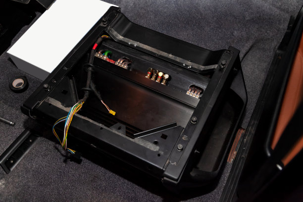 汽车音响系统的放大器安装在一个黑色的金属外壳上，安装在汽车的地板上，在修理和调试车间。汽车服务行业。图片下载