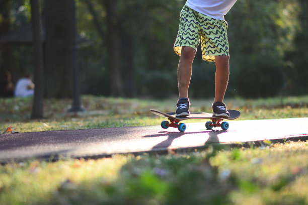 男孩玩滑板享受公园。图片下载