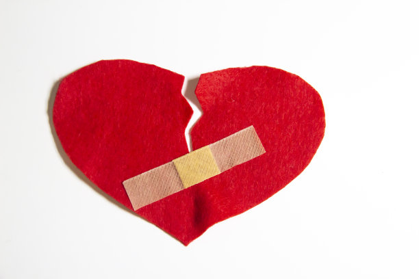 破碎的心，用创可贴粘在一起。一颗发自内心的心。一个关于破碎爱情的概念。在白色背景上隔离石膏心脏图片下载