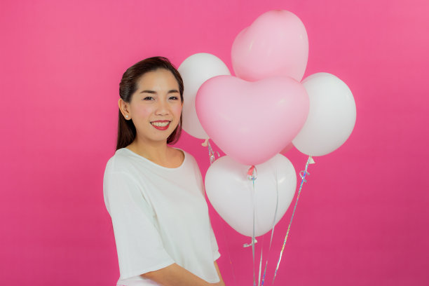 情人节的概念。美丽的笑脸亚洲女孩与粉红色的背景拷贝空间隔离。图片下载