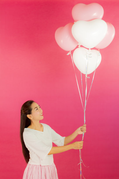 情人节的概念。美丽的笑脸亚洲女孩与粉红色的背景拷贝空间隔离。图片下载