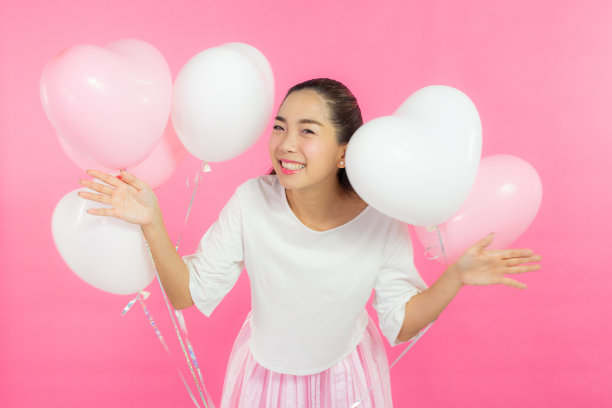 情人节的概念。美丽的笑脸亚洲女孩与粉红色的背景拷贝空间隔离。图片下载