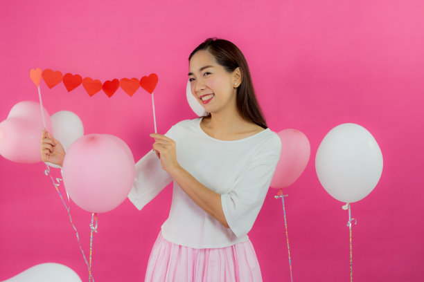 情人节的概念。美丽的笑脸亚洲女孩与粉红色的背景拷贝空间隔离。图片下载