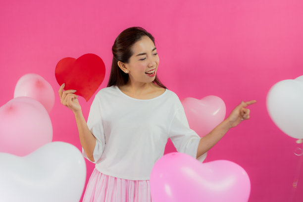 情人节的概念。美丽的笑脸亚洲女孩与粉红色的背景拷贝空间隔离。图片下载