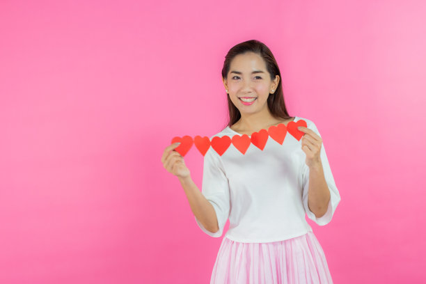 情人节的概念。美丽的笑脸亚洲女孩与粉红色的背景拷贝空间隔离。图片下载