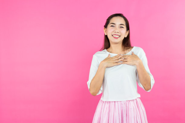 情人节的概念。美丽的笑脸亚洲女孩与粉红色的背景拷贝空间隔离。图片下载