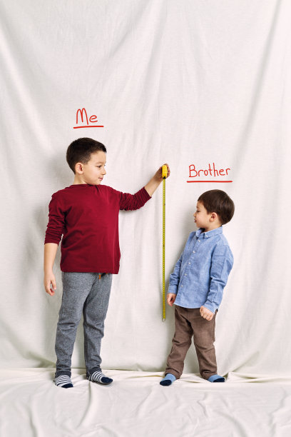 可爱的孩子在测量他的身高。成长与团队合作理念。图片下载