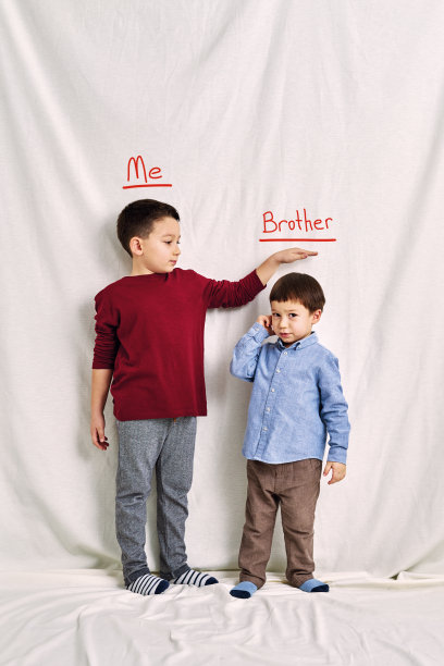 可爱的孩子在测量他的身高。成长与团队合作理念。图片下载