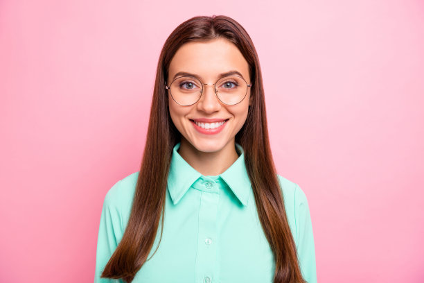 近距离的照片迷人的商务女士与惊人的白牙齿看在相机上穿眼镜蓝绿色衬衫与衣领孤立的粉红色背景图片下载